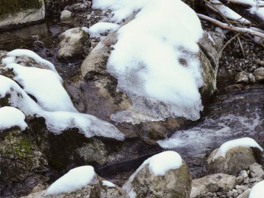 Kışın büyük karlı kayalar arasında akan akarsu akıntısını kapatın.