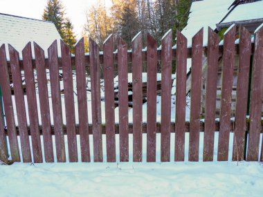 Karlı bir tarlanın önündeki kırsal kahverengi ahşap çitin simetrik görüntüsü