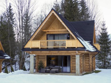 Karlı bir günde, sıcacık, ahşap bir dağ evinin önü.