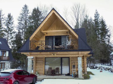 Dağlardaki karlı çimlere park etmiş arabalı ahşap yazlık ev.