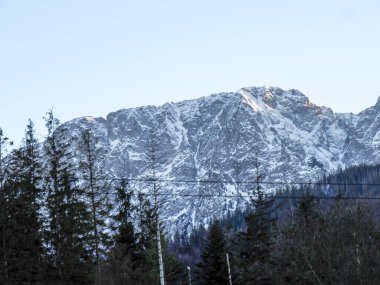 Geleneksel ahşap dağ evi. Karlı bir tepede sarı pencere ışığı var.