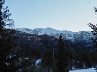 Kışın açık mavi gökyüzünün altında karla kaplı bir dağ sırtı manzarası