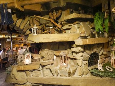 Taş ocağı ve fenerleri olan geleneksel bir Zakopane restoranının iç manzarası.