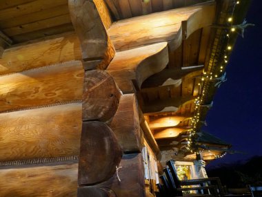 Akşamları sıcacık şenlik çelenkleriyle aydınlatılan büyük bir ahşap evin yan görünüşü