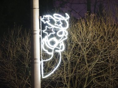 Kış ağaçlarına karşı bir direğin üzerindeki figür şeklinde dekoratif Noel ışığı kurulumu