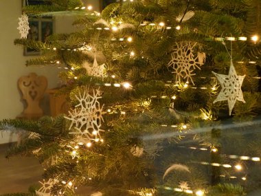 Beyaz el yapımı kar taneleri süsleri ve sıcak ışıkları olan bir Noel ağacının bulanık arkaplanı