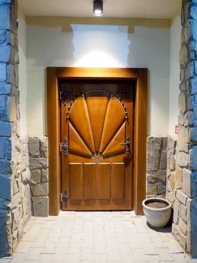 Güneş ışınları ve taş duvarlarla süslü ahşap bir kapının simetrik görüntüsü.