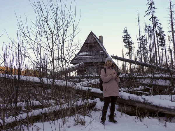 Karlı kış dağlarında sırt çantalı bir kadın turistin telefon kullanırken tam görüntüsü..