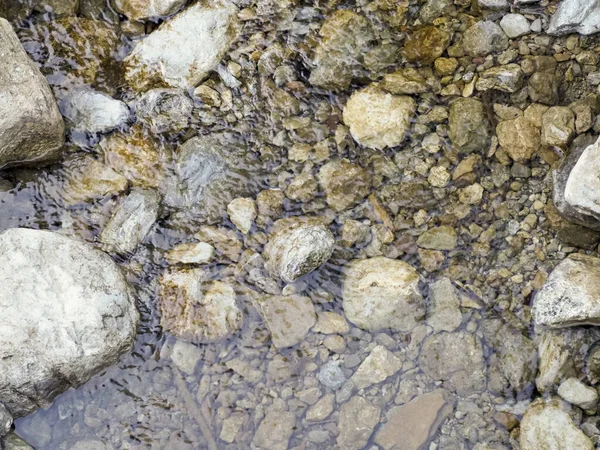 Altın kum ve su altı nehir taşlarıyla sığ nehir suyunun arkaplan dokusu