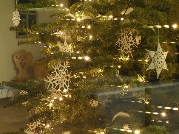 Beyaz el yapımı kar taneleri süsleri ve sıcak ışıkları olan bir Noel ağacının bulanık arkaplanı