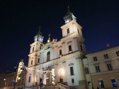 Varşova 'daki Kutsal Haç Kilisesi' nin gece görüşü aydınlık cephe ve şenlik ışıklarıyla