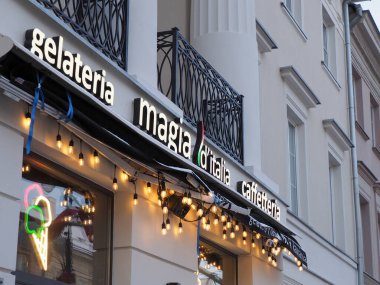 Magia d 'Italia gelateria ve caffetteria cephesinin parlak neon ve akşam ışıklarıyla yan görünüşü