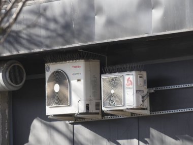 İki havalandırma ünitesi Toshiba ve Chigo gri endüstriyel bina duvarına monte edildi