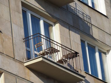 Minimalist balkon. Gri taş bir cephede basit bir tahta sandalye.