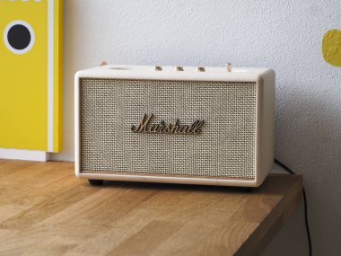 Klasik bej rengi Marshall konuşmacısı. Parlak, modern bir iç mekanda ahşap bir masanın üzerinde duruyor.