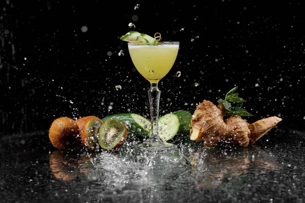 Osvěžující koktejl v cákancích vody na černém pozadí okurkové kiwi a zázvoru — Stock fotografie