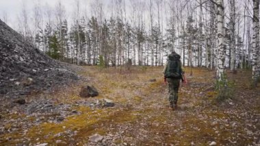 Sırt çantalı genç adam gündüz vakti ormanda yürüyor, ağır çekimde. 