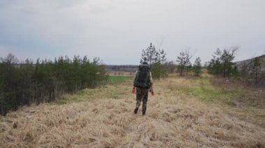 Sırt çantalı genç adam gündüz vakti ormanda yürüyor, ağır çekimde. 