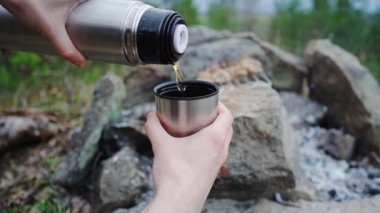 Kadın termos şişesinden metal bardağa çay dolduruyor. Yavaş çekim görüntüleri.