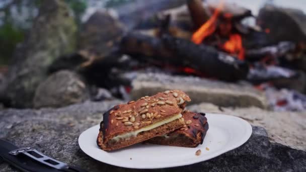 有种子和奶酪的油炸面包躺在篝火边的石头上 慢镜头 — 图库视频影像