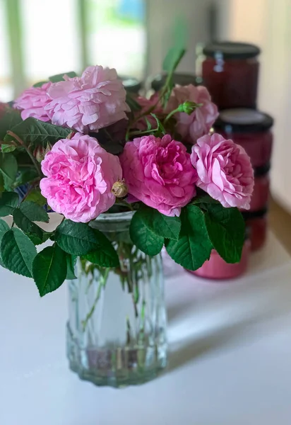 A vase filled with rose centifolia on a table