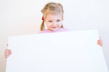 Üç yaşında çekici bir kız elinde bir kağıt parçası tutuyor.