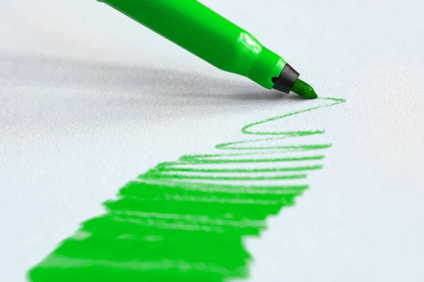Green felt tip pen draws on white paper Stock Photo
