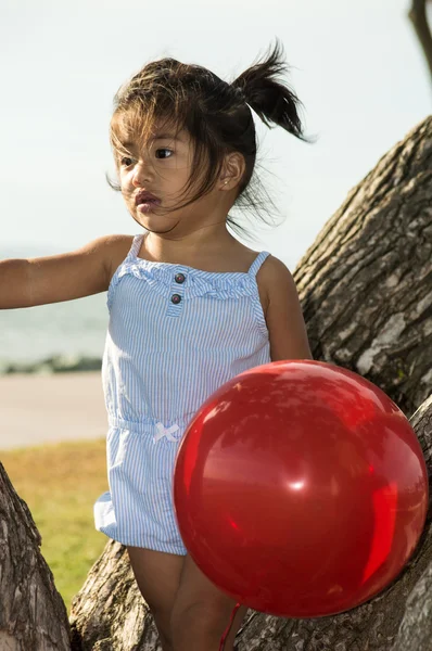 Balon olan bir ağaç, küçük kız