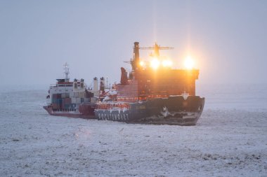 Sabetta, Tyumen bölgesi, Rusya - 4 Nisan 2021: 50 Pobedy 'nin buz üzerinde bir kargo gemisini çekmesine izin verdi. Bulutlu, hafif kar yağıyor.
