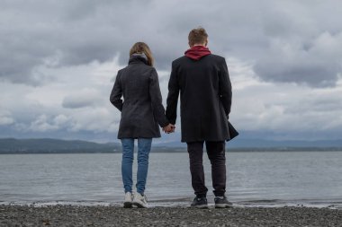 Genç kadın ve erkek el ele tutuşuyor. Aşkları var..