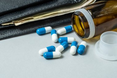 Masaya saçılmış tıbbi haplar. Cüzdanın arka planında para var..