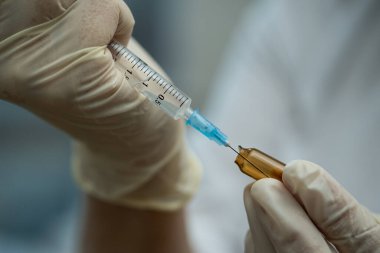 Doktorun elinde tıbbi ampul ve şırınga var..