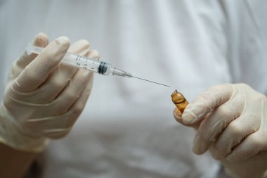 Doktorun elinde tıbbi ampul ve şırınga var..