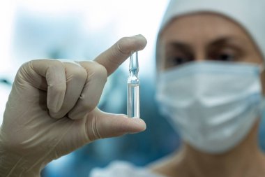 Doktor elindeki tıbbi ampule bakıyor..