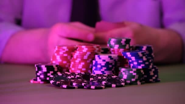 男はカジノで遊んでいる テーブルの上にはチップと手だけが表示されます 背景はとてもぼやけています — ストック動画