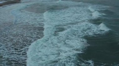 Sığ bir kıyı şeridinde akan deniz dalgaları.