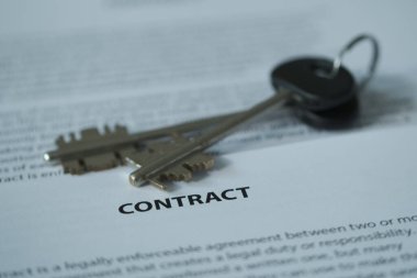 Masanın üzerinde bir sözleşme ve araba anahtarları var, vurgu belgenin adı ve anahtarlar üzerinde. Bulanık resim.