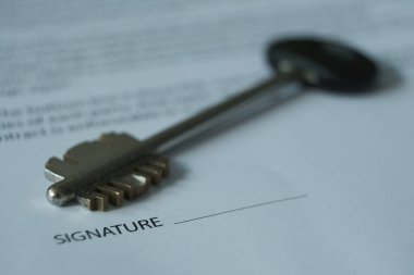 Kontrat var ve odanın anahtarları masanın üzerinde, anahtar ve imzalanacak yerler üzerinde duruluyor. Bulanık resim.