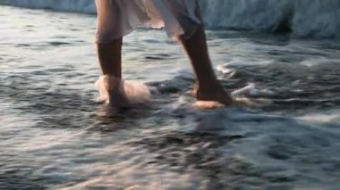 Sörf, köpüklü bir dalga kadının ayaklarını yıkar..