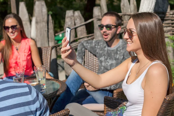 Jóvenes amigos riendo y tomando fotos al aire libre —  Fotos de Stock