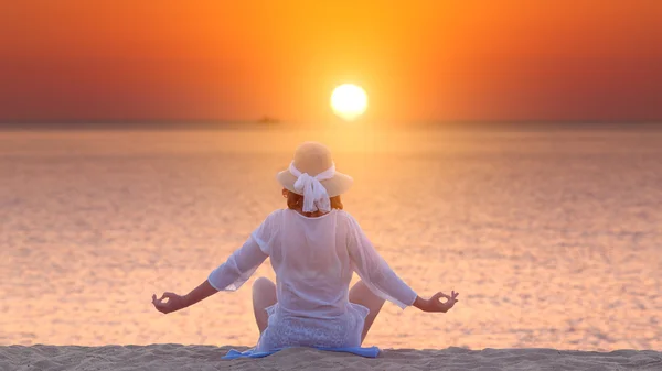 Mulher meditando em ioga posar na praia ao pôr do sol bonito — Fotografia de Stock