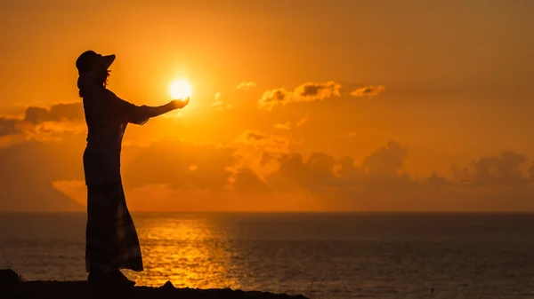 Mujer silueta sosteniendo el sol con un fondo cálido —  Fotos de Stock