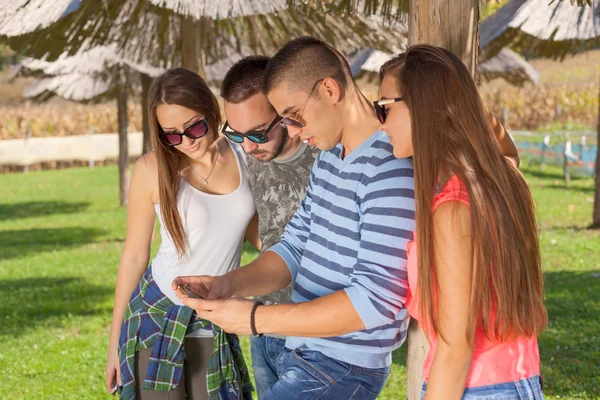 Jóvenes amigos divirtiéndose y jugando con el teléfono al aire libre —  Fotos de Stock