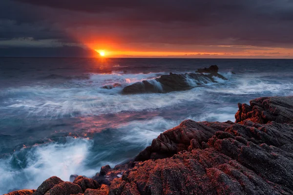 Dramatischer Sonnenaufgang mit Wellen und Felsen in Richtung Sonne — Stockfoto