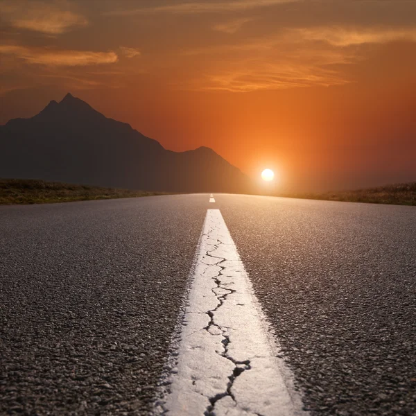 Rijden op de openbare weg richting de berg bij zonsondergang — Stockfoto