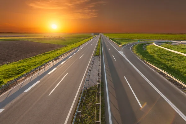 Abrir auto-estrada através de campos agrícolas verdes iluminados — Fotografia de Stock