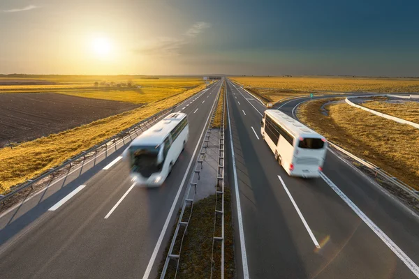 Szybkiej podróży autobusami na autostradzie w idyllicznym zachód słońca — Zdjęcie stockowe