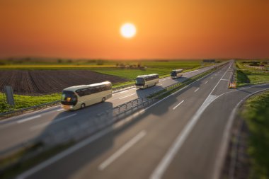Tilt shift görüntü gün batımında karayolu üzerinde hızlı seyahat otobüs