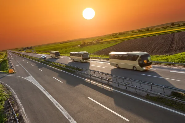 Gün batımında karayolu üzerinde üst üste hızlı seyahat otobüsleri