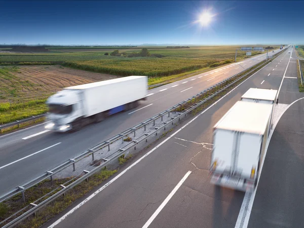 Dvě bílé kamiony na dálnici na slunečný den — Stock fotografie